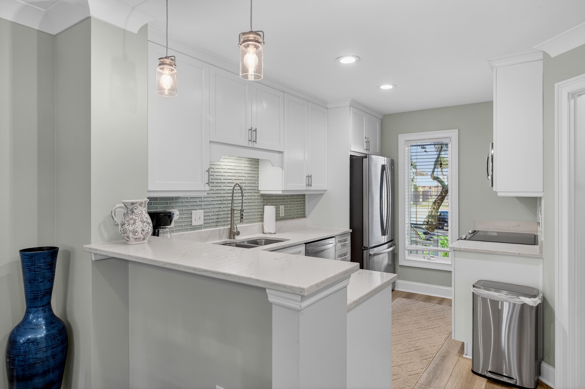 Bright, modern kitchen featuring white cabinetry, gleaming countertops, and stainless appliances—your perfect space to create delicious meals during your stay.