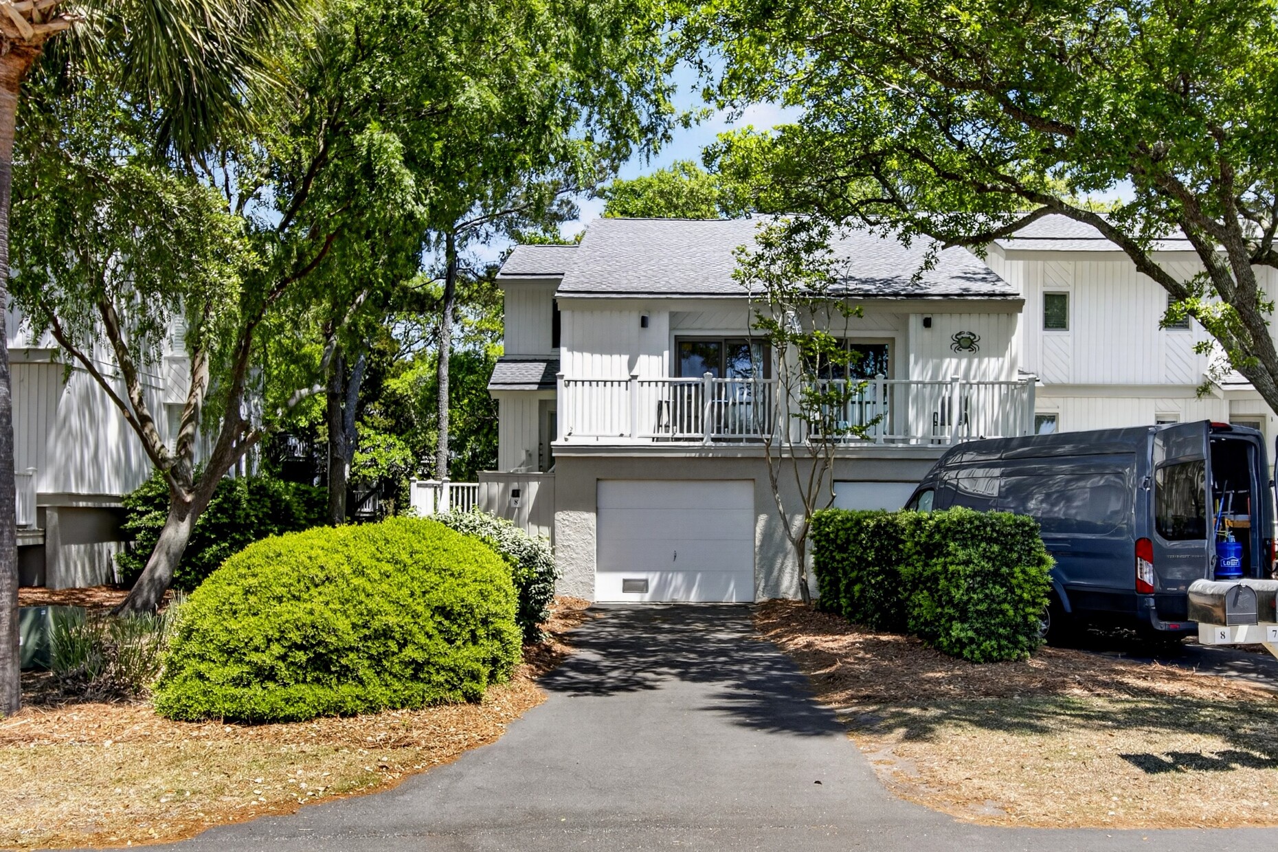 Modern two-story vacation home nestled among mature trees with convenient parking and welcoming balconies.