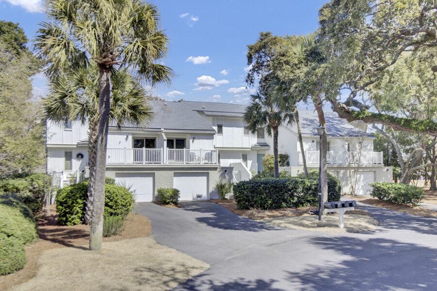 A peaceful coastal-style property nestled among mature palms and live oaks, offering a serene retreat with private parking and charming balcony spaces in a tree-shaded neighborhood.