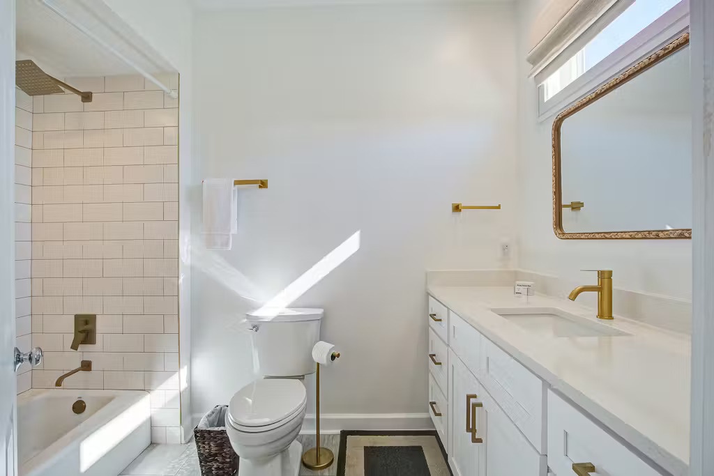 Your private bathroom features elegant gold fixtures, subway tile shower, and bright natural light for your daily refresh.