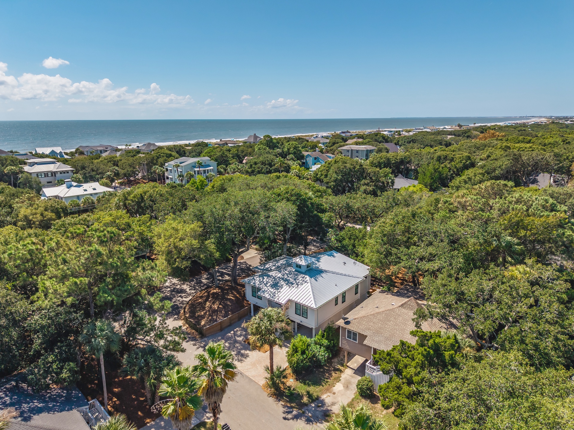 This coastal property sits nestled among lush greenery with the sparkling ocean just beyond, offering a peaceful retreat surrounded by natural beauty and nearby beach access.