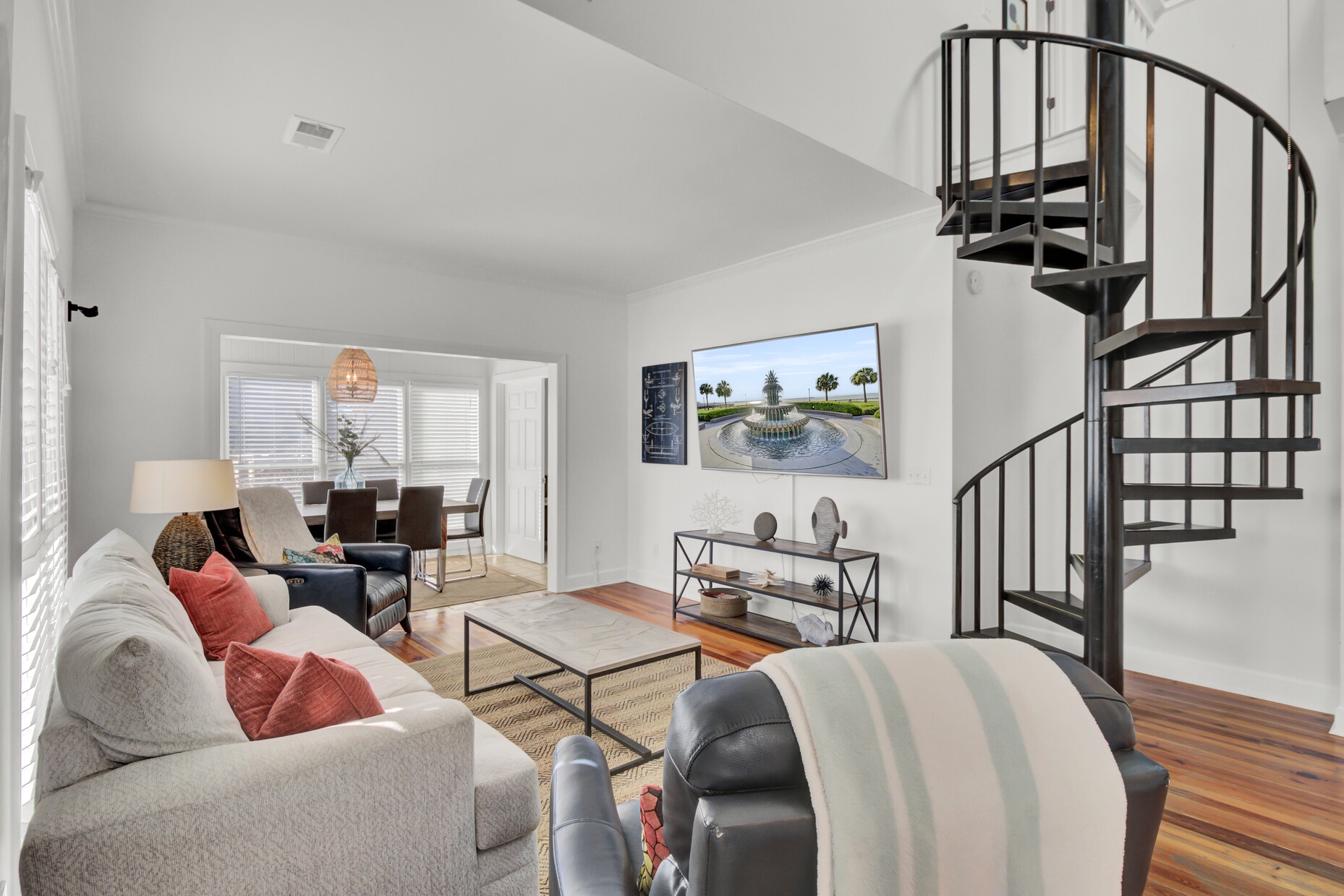Relax in your bright living space featuring a striking spiral staircase, cozy seating, and modern style throughout.