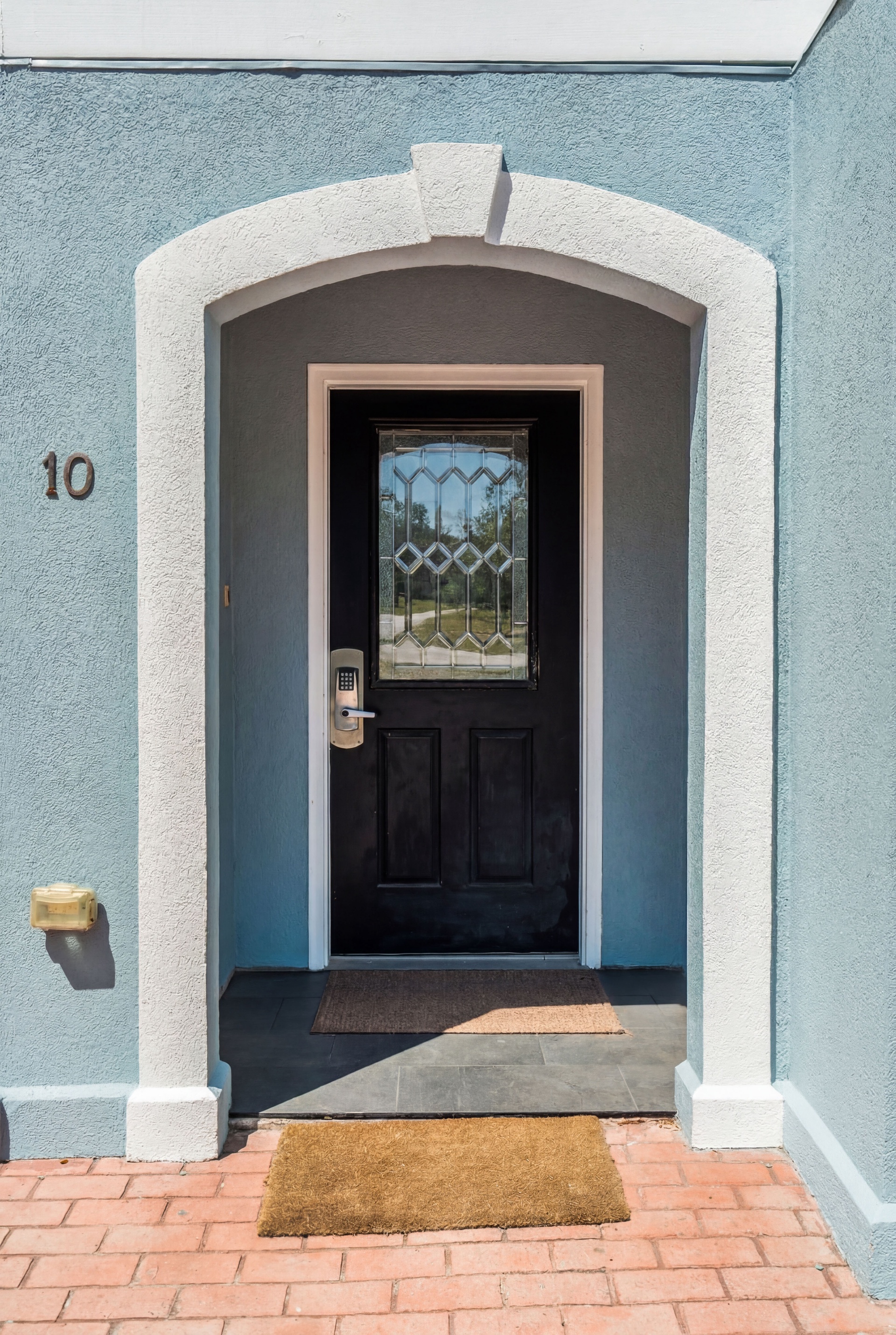 The entrance to your vacation retreat features a charming arched doorway with decorative glass, welcoming you to unit 10 with a keypad entry for easy, secure check-in.