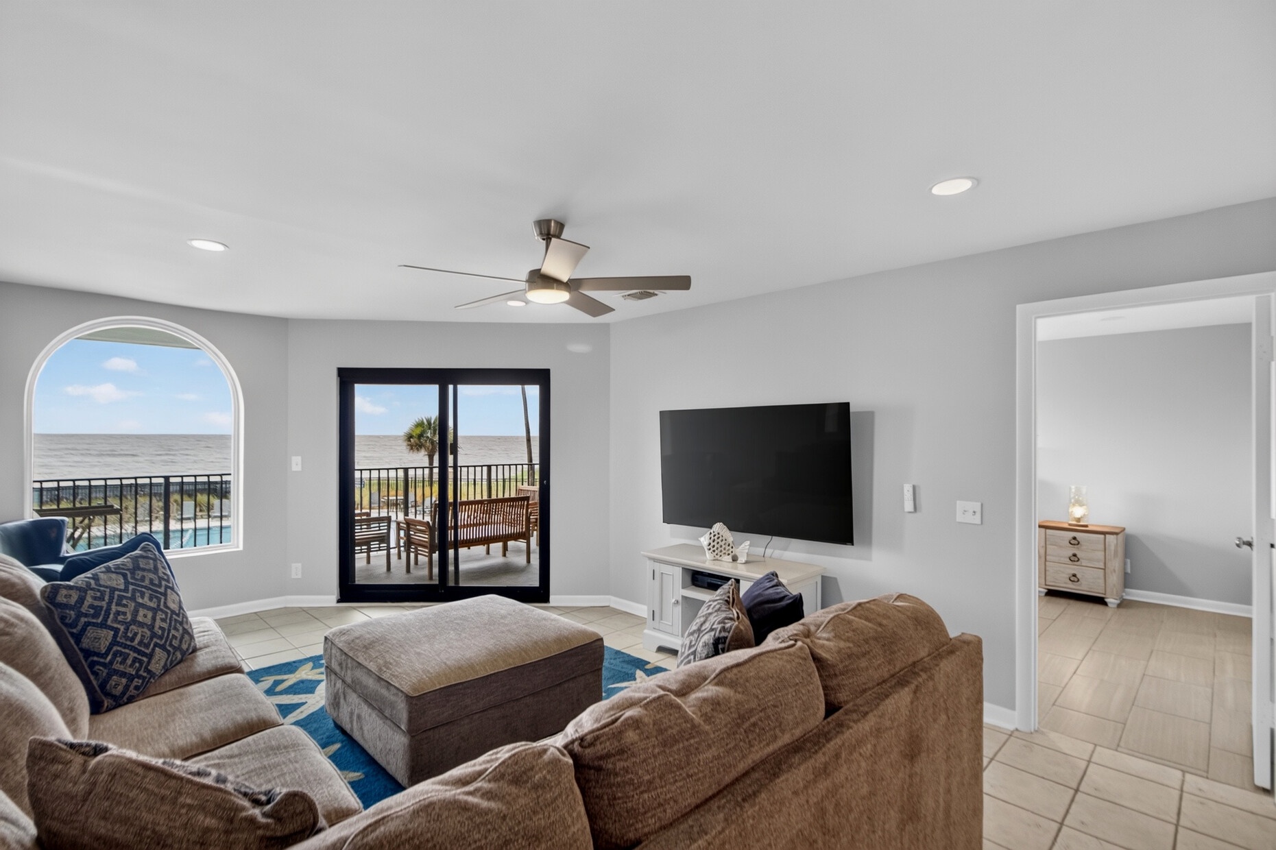 Settle into your oceanfront retreat with plush seating, a ceiling fan, and balcony doors opening to panoramic views. Your coastal escape awaits just steps away.