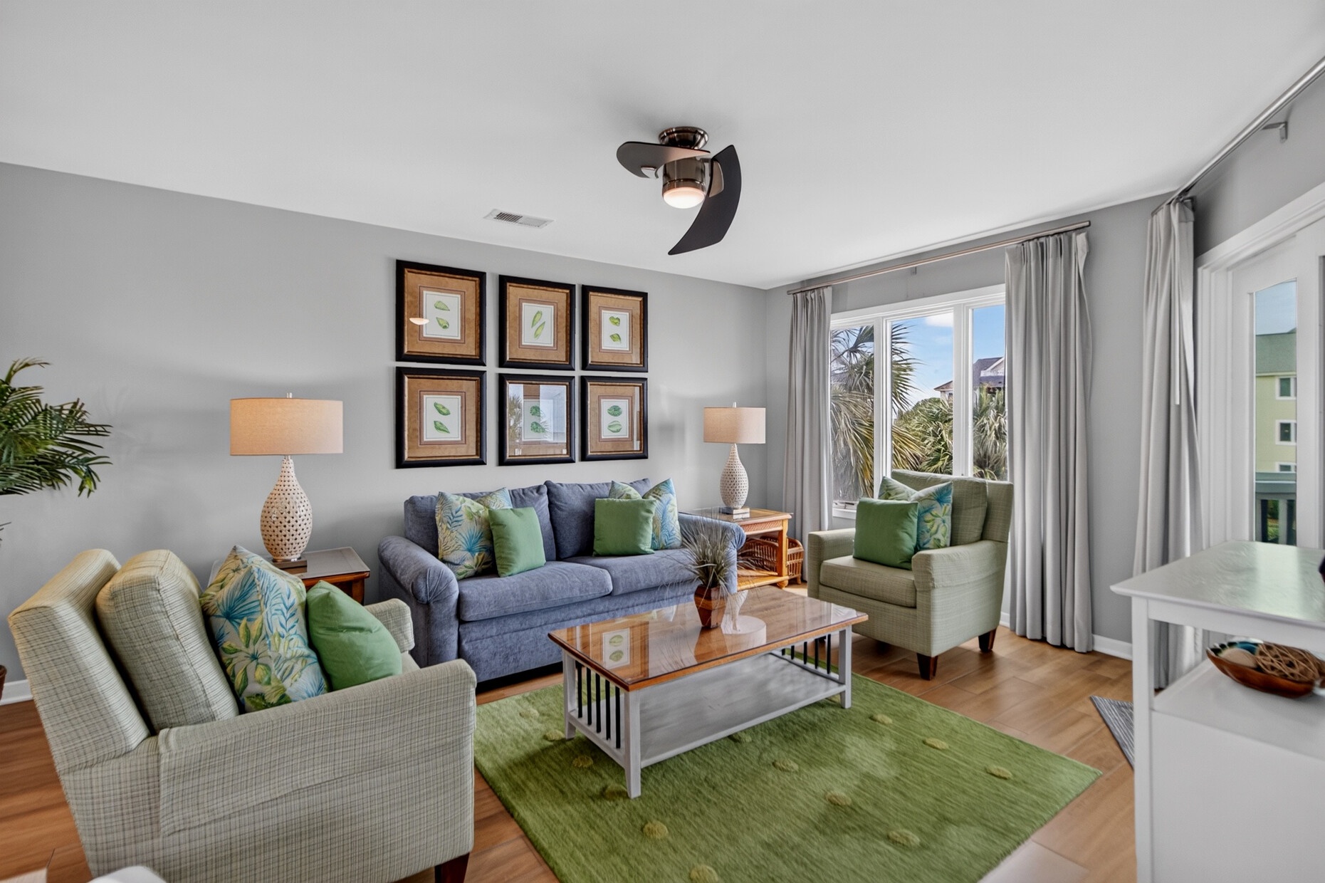 Unwind in this inviting living space with soft seating, tropical touches, and natural light streaming through palm-framed windows—your perfect coastal retreat.