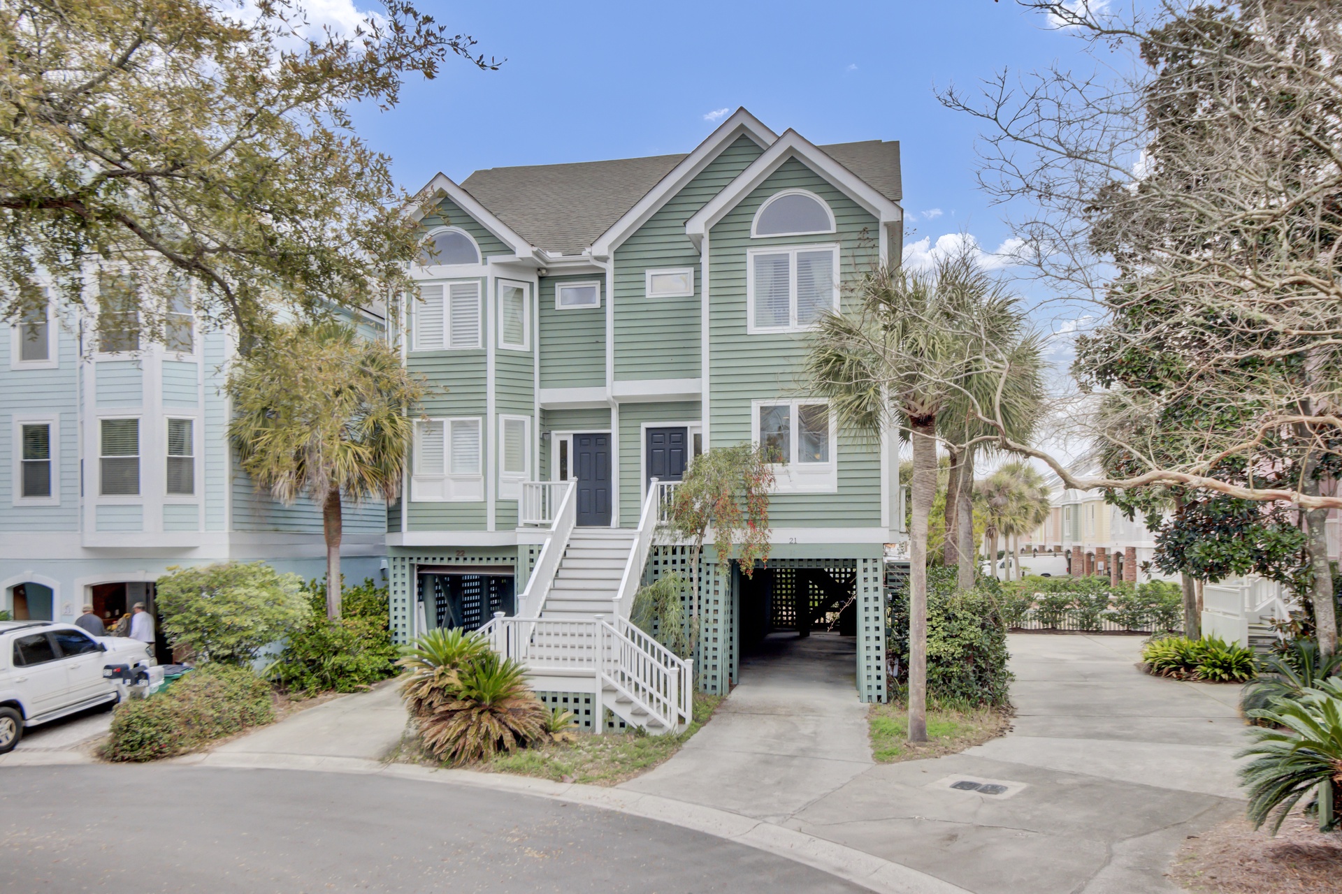 Charming coastal duplex with tropical landscaping and convenient ground-level parking in a peaceful residential setting.