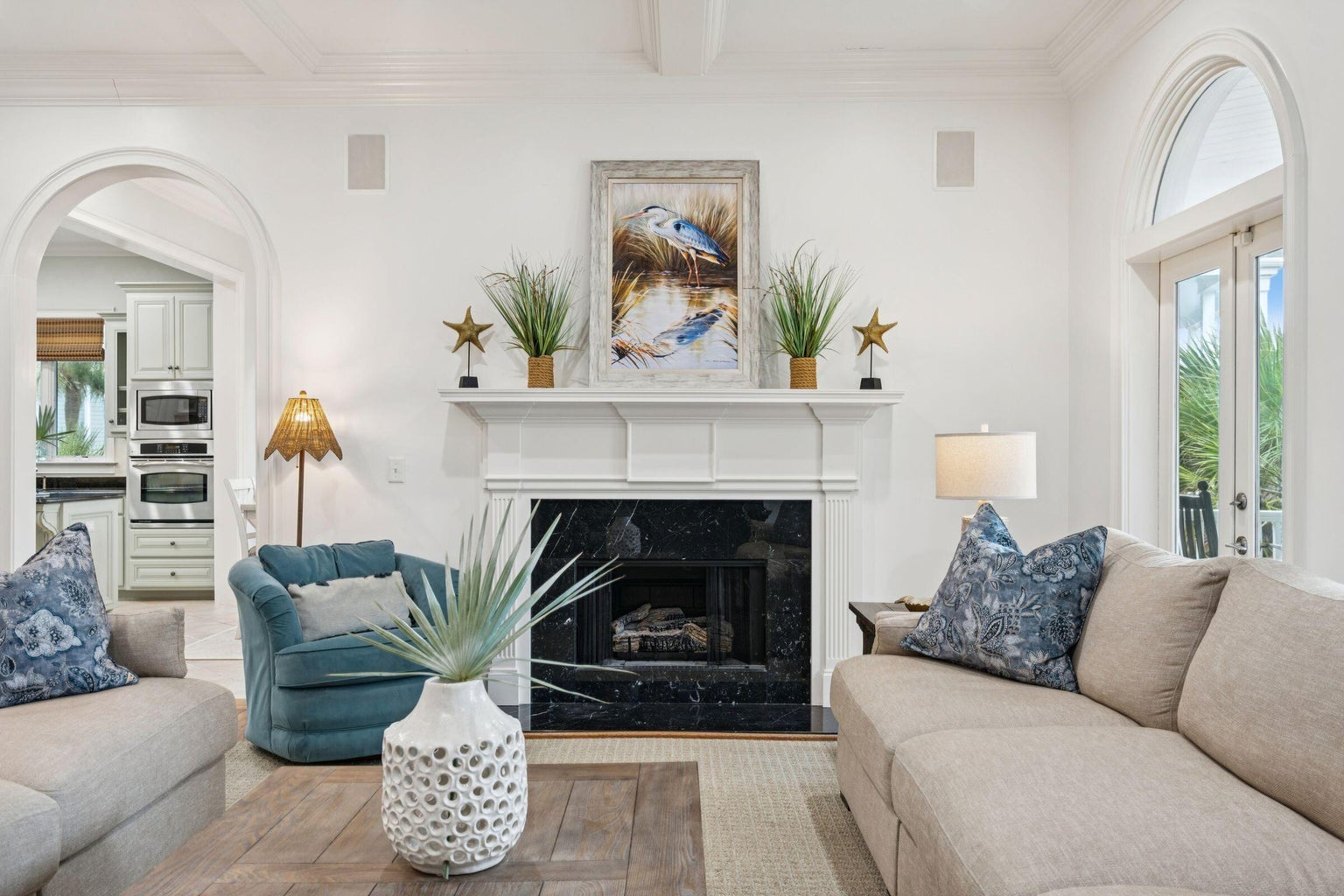 Sink into plush sofas by your elegant fireplace, where coastal artwork and soft lighting create the perfect atmosphere for relaxing evenings.