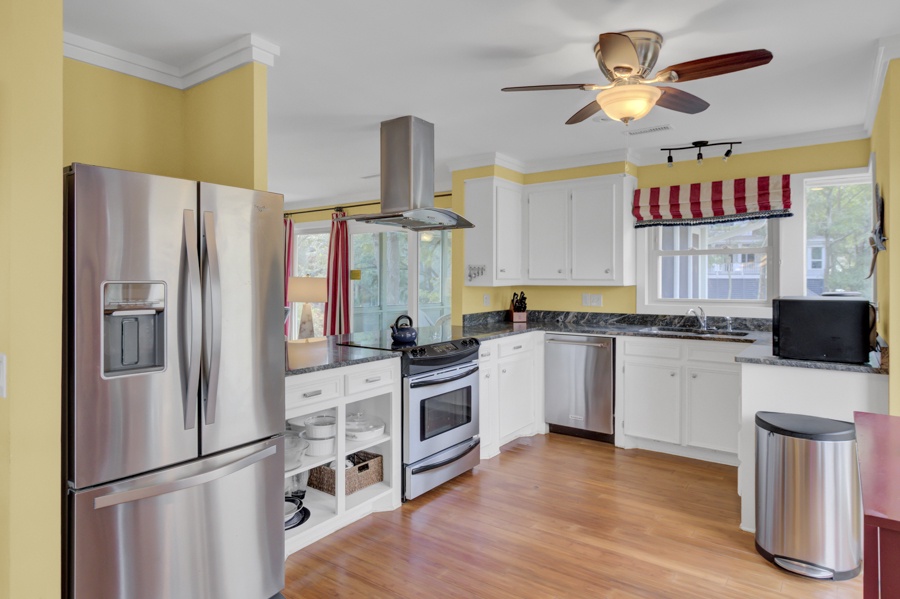 Your fully equipped kitchen awaits with stainless steel appliances, granite countertops, and cheerful yellow walls creating the perfect space for home-cooked meals.