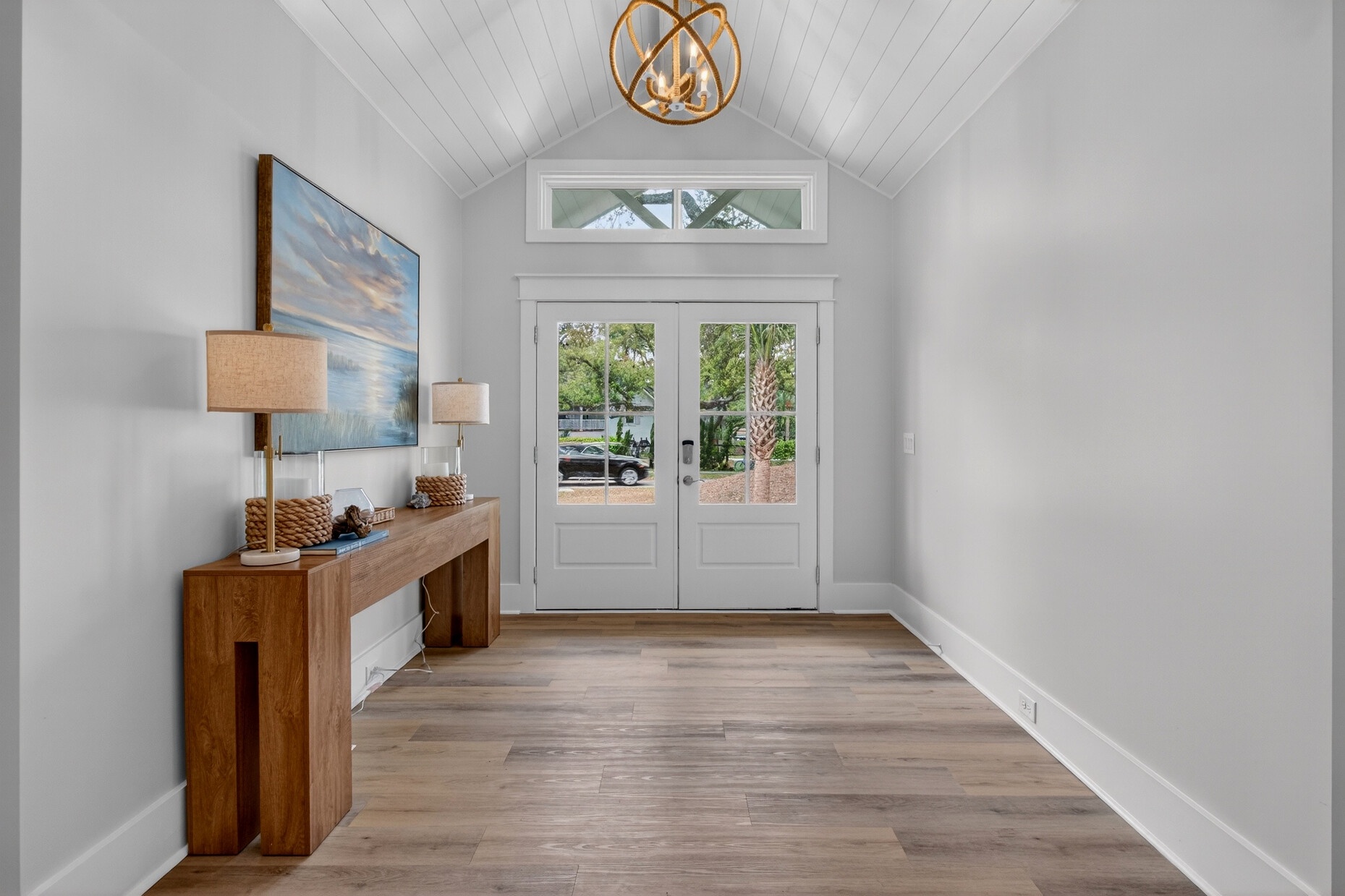 You're welcomed by soaring vaulted ceilings and warm wood floors in this elegant entryway, where natural light streams through French doors.
