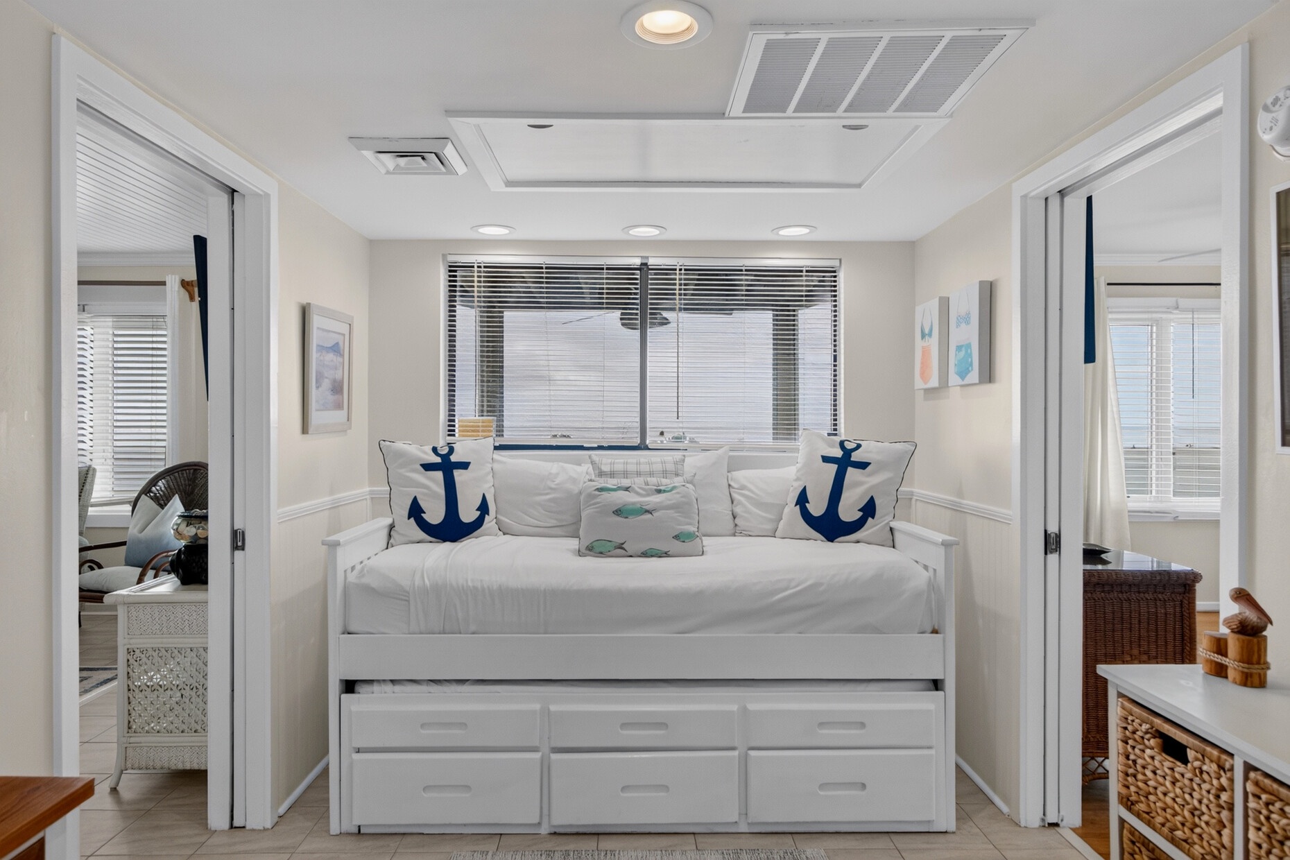 Relax in your airy coastal retreat with a nautical-inspired daybed, built-in storage, and soft natural light filtering through plantation blinds—your perfect beach house escape.