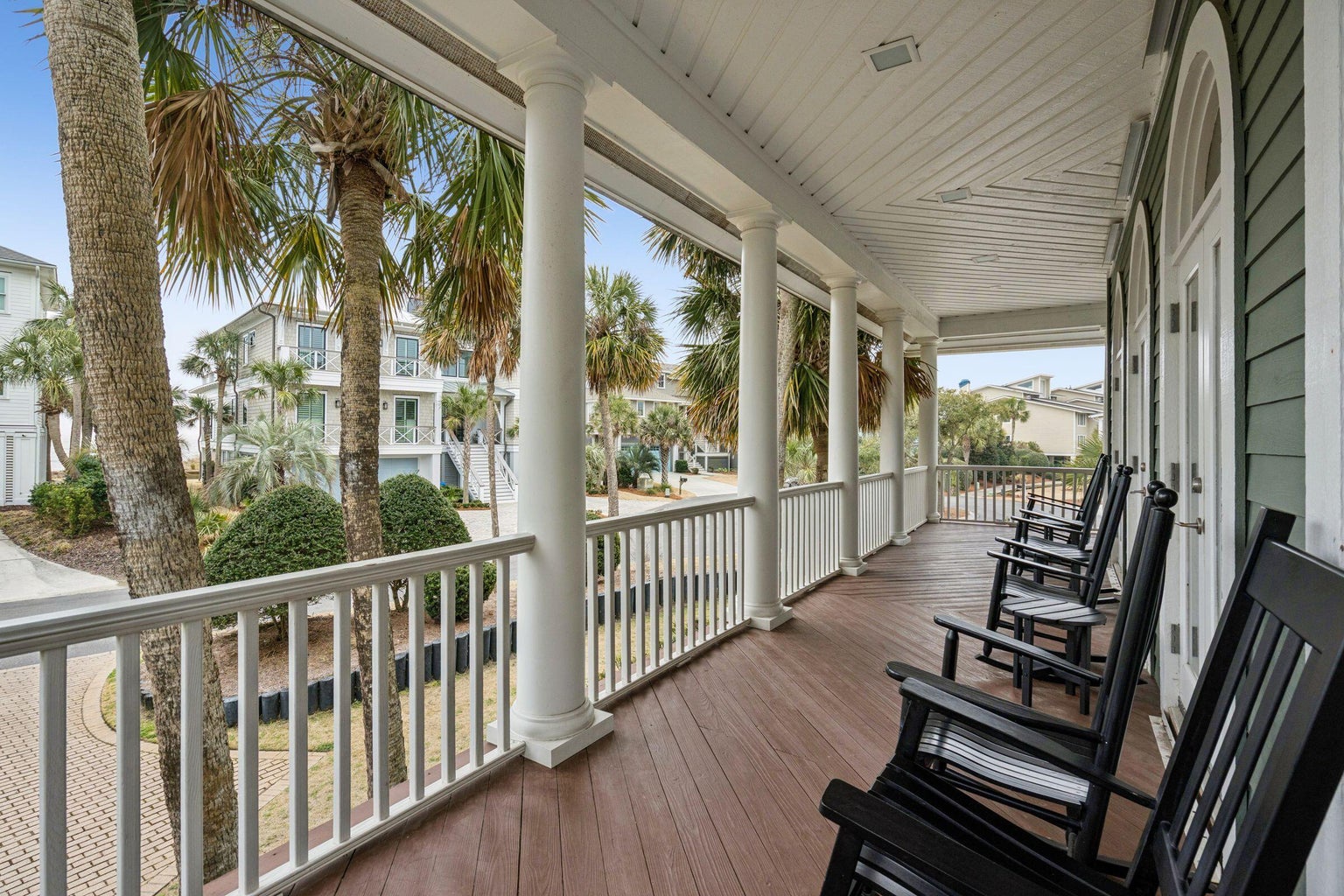 Settle into your rocking chair on this peaceful wraparound porch, where palm trees sway and coastal breezes invite you to unwind completely.