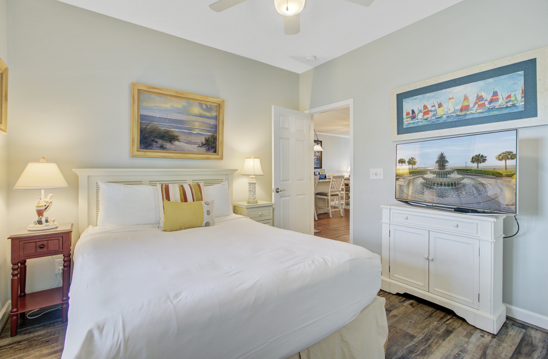 Sink into crisp white linens in your coastal-themed bedroom, where nautical artwork and warm lighting create a serene retreat after your adventures.