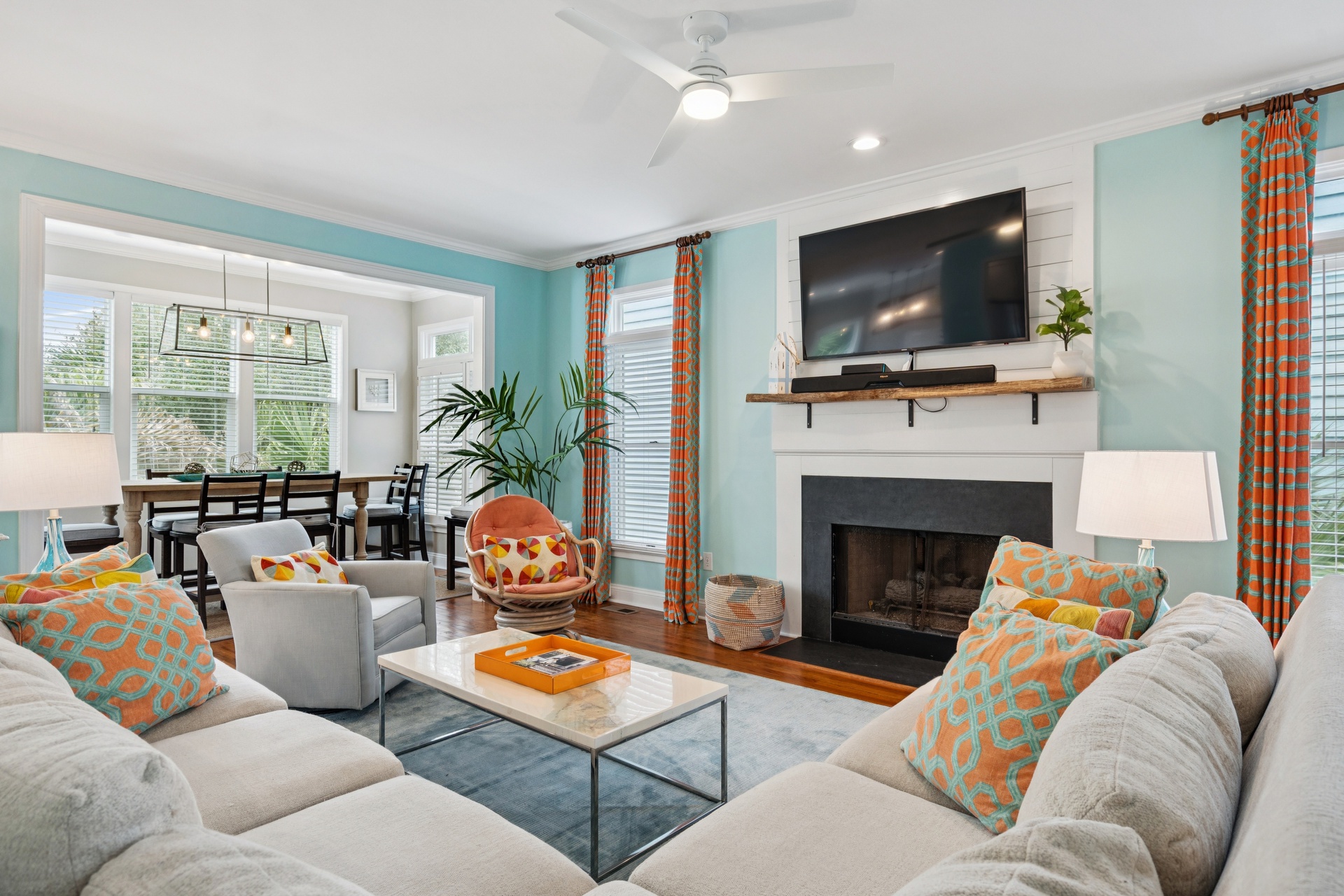 Relax in your bright, coastal-themed living space with plush seating, cozy fireplace, and cheerful orange accents throughout.