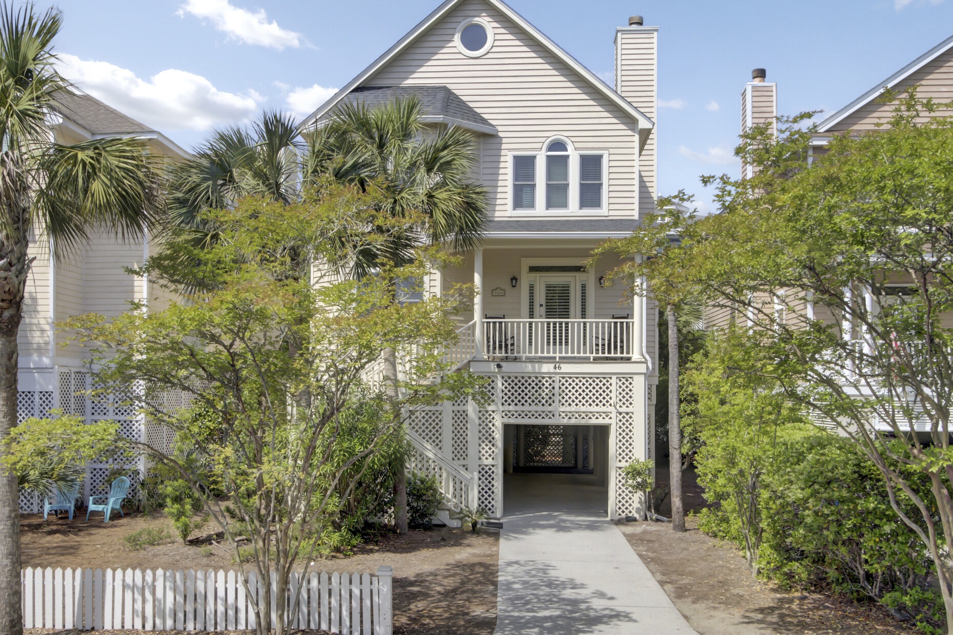 Charming coastal cottage with front porch and tropical landscaping, nestled in a peaceful residential neighborhood.