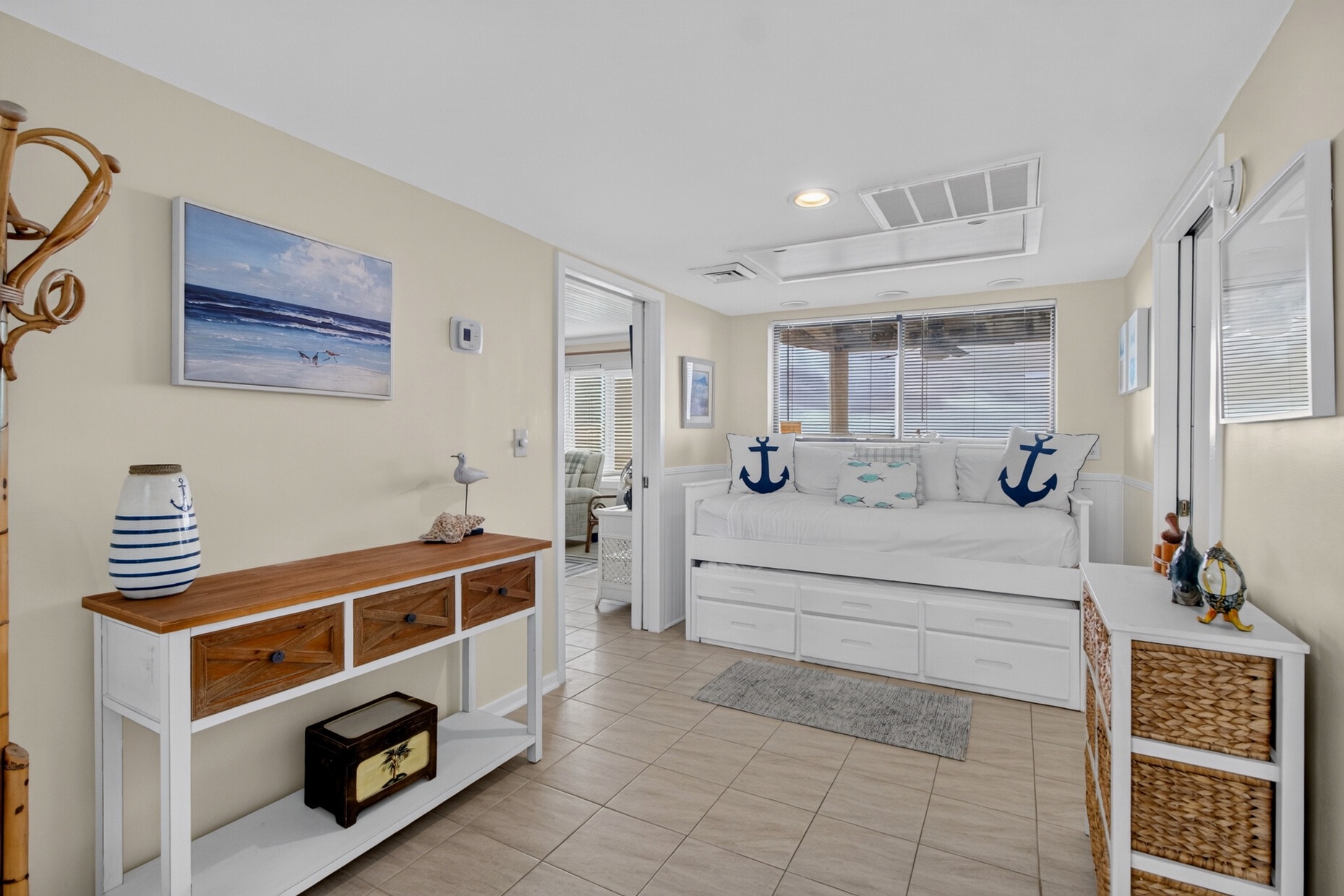 Step into your nautical-inspired retreat, where crisp whites and coastal blues create a serene atmosphere. Your daybed invites restful moments, while storage baskets and thoughtful decor bring beach charm to this bright, tile-floored sanctuary.