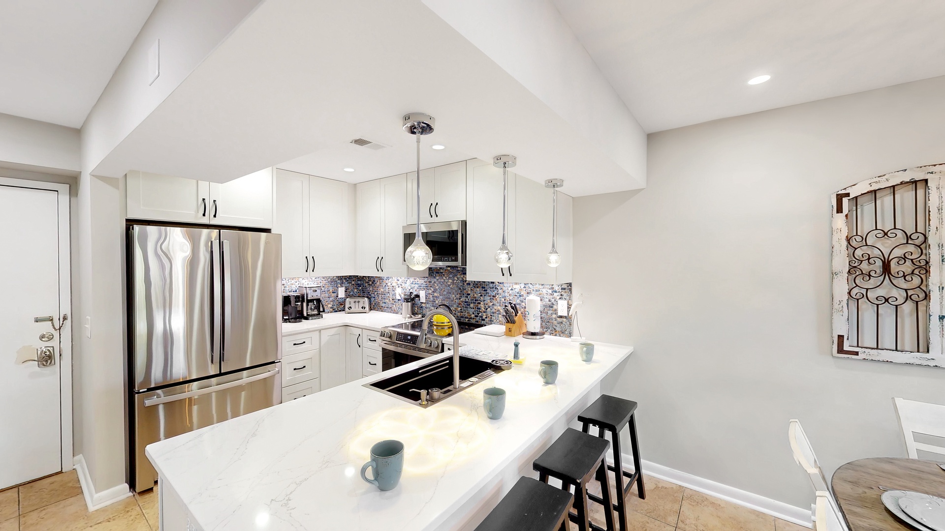 Your gourmet kitchen features sleek white cabinetry, gleaming marble countertops, and stainless steel appliances—perfect for crafting morning coffee at the island or preparing a feast under vaulted ceilings with warm pendant lighting.