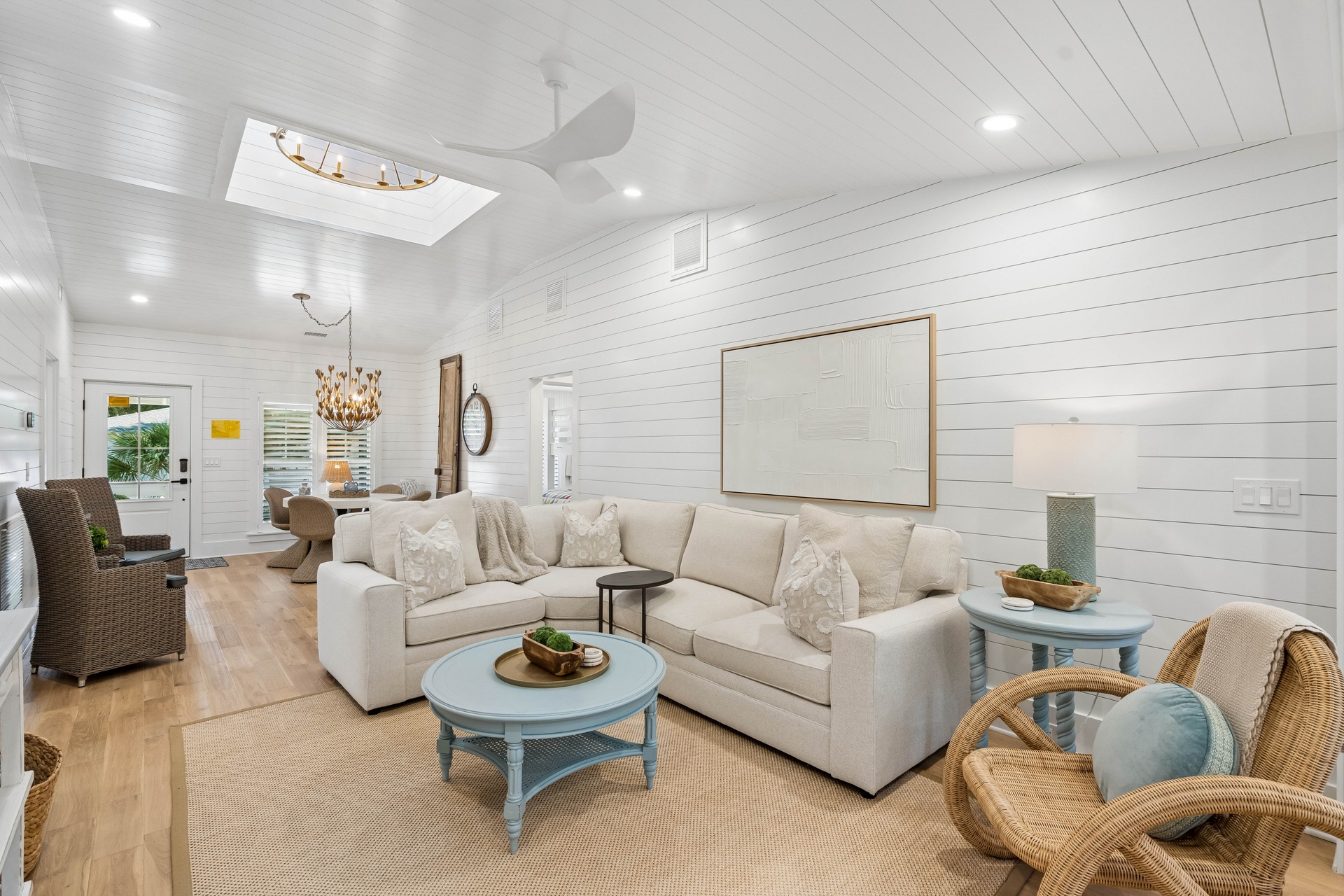 Sink into the plush sofa and unwind in this bright, airy living room with its vaulted shiplap ceilings, natural light streaming through the skylight, and coastal charm that invites you to relax.