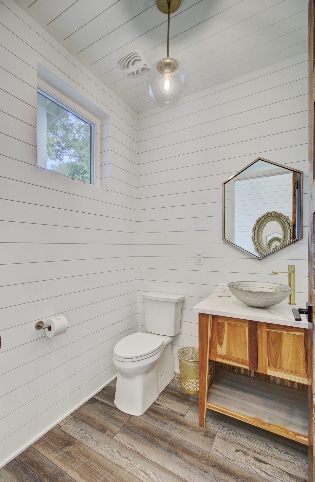 Unwind in this stylish powder room featuring white shiplap walls and warm wood accents that create a perfect blend of farmhouse charm and modern comfort.