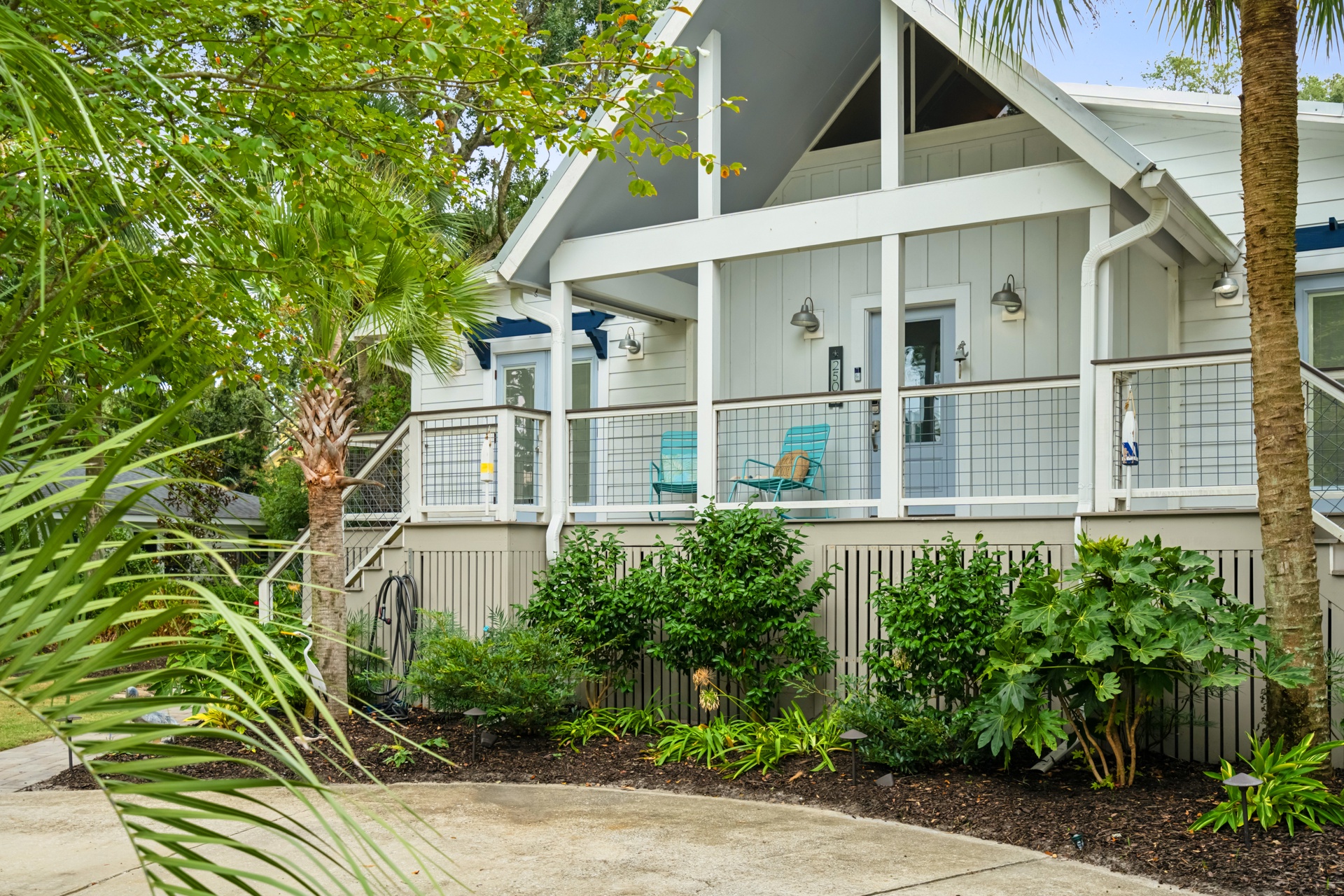 Charming coastal-style home nestled among tropical palms and lush greenery. An elevated porch with inviting seating welcomes you to this private retreat where island living meets modern comfort.