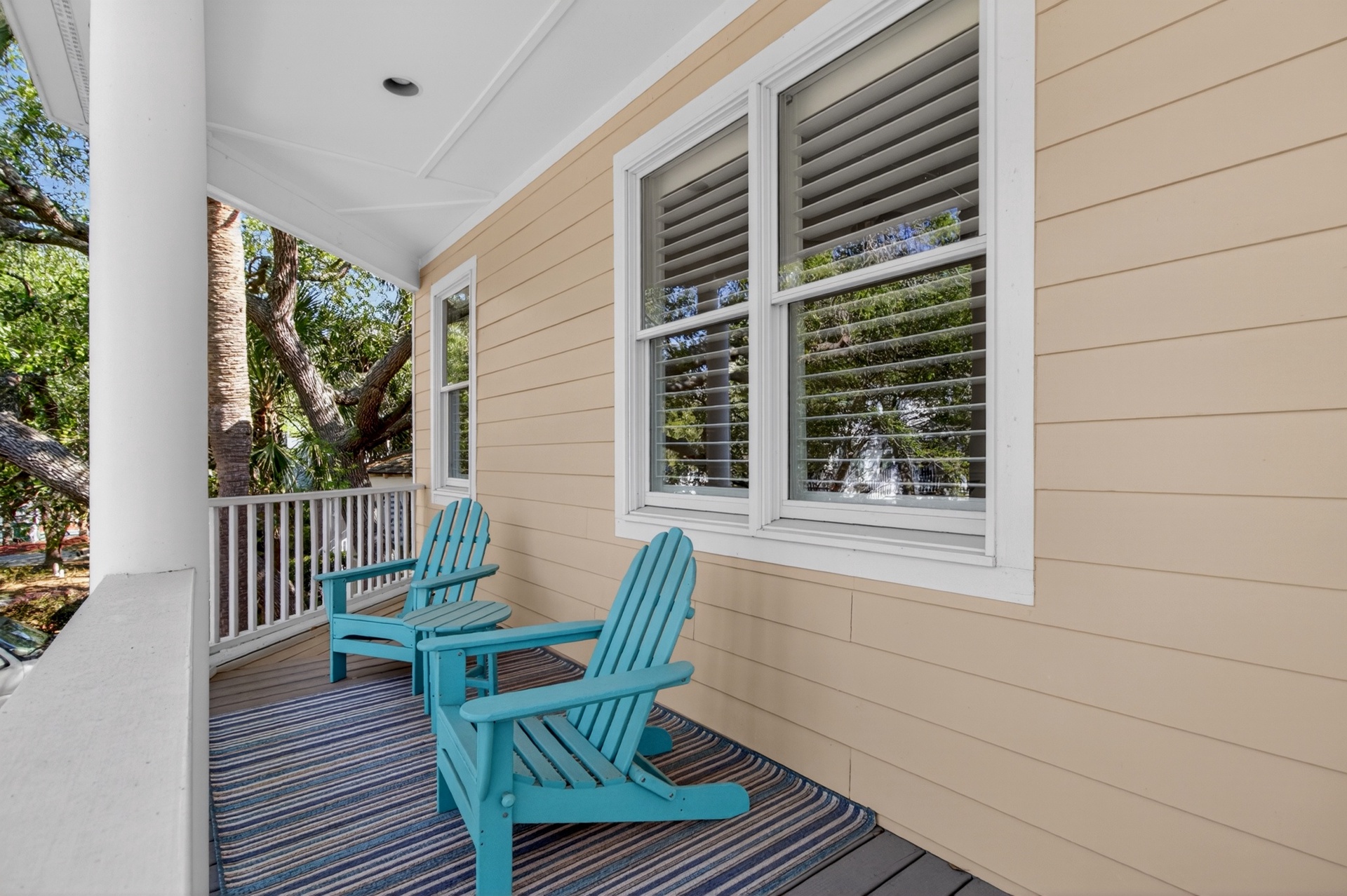 Step onto your private covered porch and sink into vibrant turquoise Adirondack chairs, where you'll sip morning coffee surrounded by lush tropical greenery.