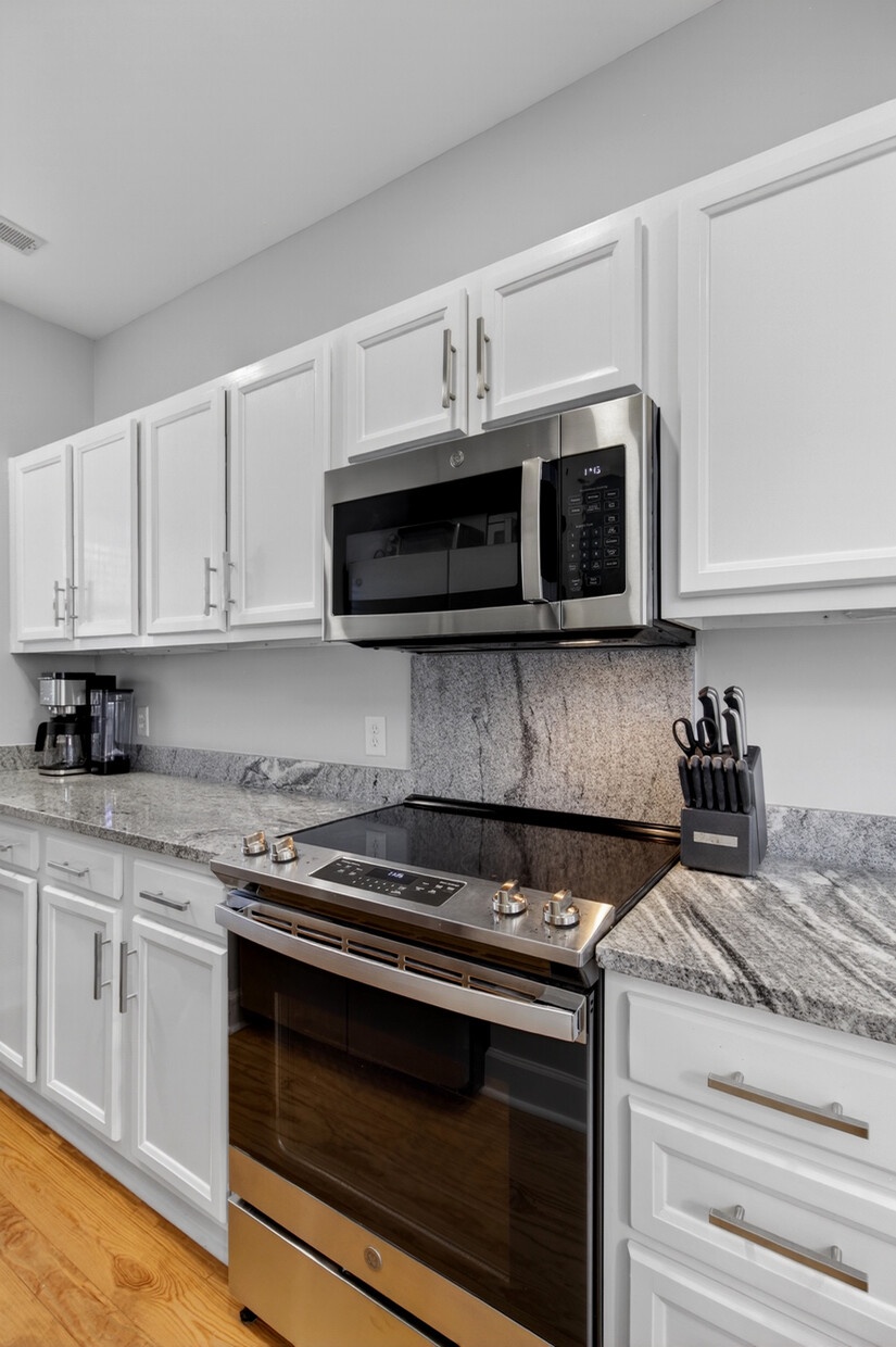 Cook your favorite meals in this sleek kitchen with granite countertops, stainless steel appliances, and crisp white cabinets.