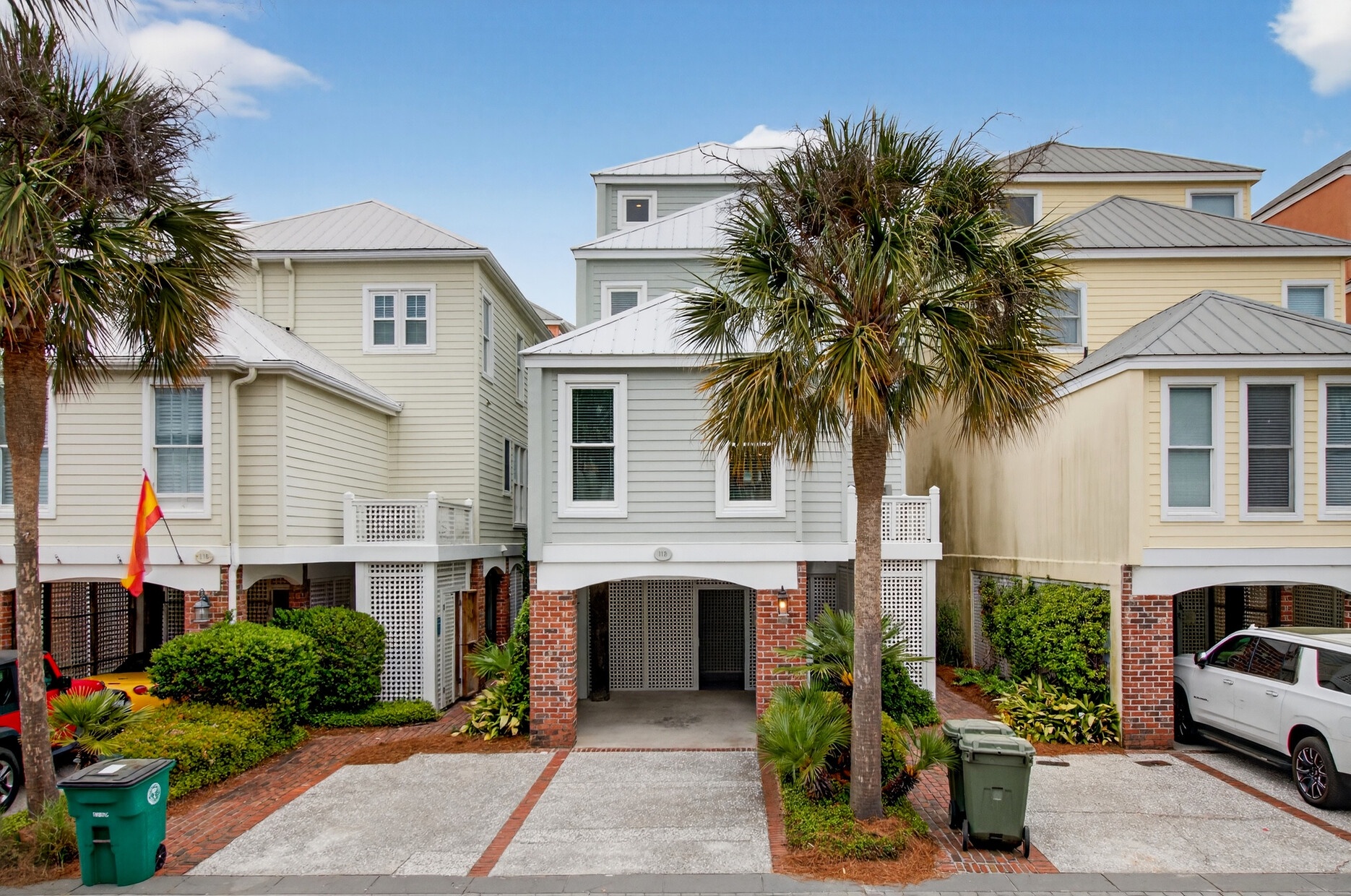 Charming coastal townhomes with palm trees and brick accents create a welcoming beachside community setting.