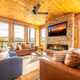 Unwind in your expansive living room where floor-to-ceiling windows frame stunning mountain views, while the stone fireplace and plush seating invite cozy evenings with friends and family.
