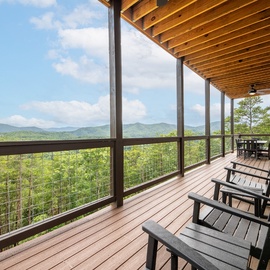 Relax in your outdoor lounge chairs and soak in breathtaking mountain vistas from this expansive covered deck, where the beauty of nature stretches endlessly before you.