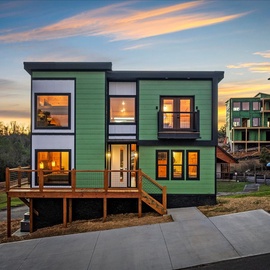 Modern green facade stands bright against the evening sky, creating a stunning arrival experience in this distinctive neighborhood.
