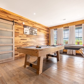 Challenge your travel companions to a friendly game in this spacious game room, where warm wood tones and natural light through large windows create the perfect setting for fun and relaxation.