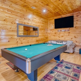 Your game room awaits with a professional pool table, cozy seating, and big screen TV for perfect cabin entertainment nights.