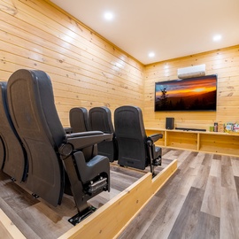 Your private theater features plush reclining seats and rustic wood walls, creating the perfect cozy retreat for movie nights.