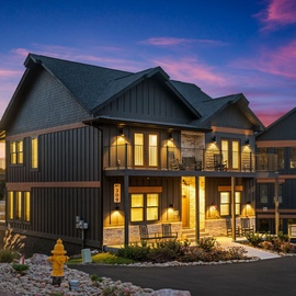 Modern mountain lodge illuminated under a stunning twilight sky.