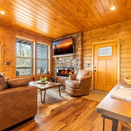 Unwind in your cozy living room where warm wood surrounds you and the crackling fireplace creates perfect ambiance for relaxing evenings.