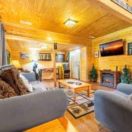 Relax in your cozy cabin living room, where warm knotty pine walls and a glowing fireplace create the perfect woodland retreat for family game nights or quiet evenings in.