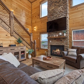 Sink into plush leather sofas by the stone fireplace, where natural wood walls and soaring ceilings create your perfect mountain retreat for cozy evenings.
