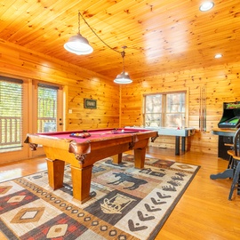 Challenge your group to pool in this inviting game room, complete with an arcade cabinet and warm wood interiors. Natural light streams through large windows, making it perfect for creating lasting memories together.