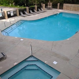 An aerial view shows the resort's pool area, surrounded by lounge chairs and natural stone walls.