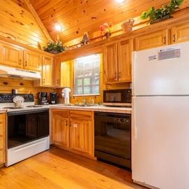 Step into a welcoming cabin kitchen with warm wood cabinetry, full appliances, and vaulted ceilings. Everything you need to cook, relax, and feel at home during your mountain getaway.