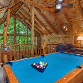 Challenge your friends to a friendly game in this lofted retreat, where soaring wood-beam ceilings and forest views create the perfect backdrop for your mountain getaway fun.