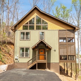 Modern mountain retreat with striking architecture nestled among tall trees, featuring warm wood accents and contemporary design elements.