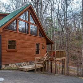 Charming mountain cabin with stunning triangular windows and wraparound deck nestled in peaceful woods.
