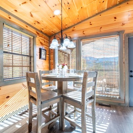 Gather around this cozy dining table while soaking in breathtaking mountain views through floor-to-ceiling windows in your rustic cabin retreat.