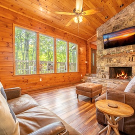 Curl up in plush leather seating before a crackling stone fireplace, surrounded by warm wood and towering vaulted ceilings. Your peaceful forest view awaits just beyond the windows.