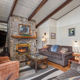 Cozy up by your crackling stone fireplace after mountain adventures, surrounded by warm furnishings and exposed beams.