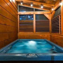 Soak away your stress in your private hot tub, surrounded by warm wood walls and gentle evening lighting.