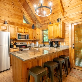 Your cabin getaway features a fully equipped kitchen with warm wood finishes, granite countertops, and modern stainless appliances.