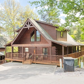 Charming log cabin with wraparound deck nestled among tall trees, offering a peaceful woodland retreat.