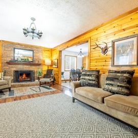 Cozy up in your rustic cabin living room, where warm wood walls and a crackling fireplace create the perfect mountain retreat atmosphere.