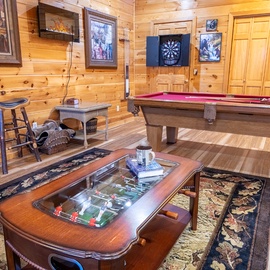 Step into your game area where warm wood walls create the perfect backdrop for friendly competition with pool, darts, and tabletop games.